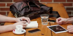Two men collaborate at a table with a laptop and coffee, discussing rental property project management for investors.