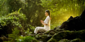 In a tranquil forest, a woman engages in meditation, finding peace and focus in her natural surroundings.